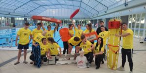 Grupo de alumnos posando en la piscina con materiales de rescate durante el curso de socorrismo acuático.